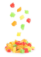 Tasty pieces of candied fruits falling into pile on white background