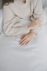Woman hands. Woman closeup picture without face on neutral background. White interior. Very soft and nice light. Healthy and clean skin. Comfort and calm. French manicure. Good nails. Beige sweater