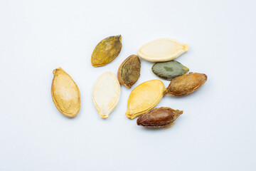 Different colorful  Dry Roasted Pumpkin seeds on white background. Tasty and healthy food. Close up photo.
