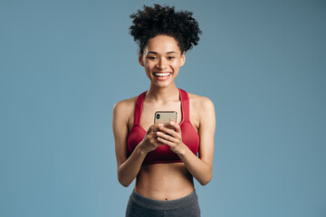 Multiracial woman looking at the camera with cheery smile and checking time at her smartphone