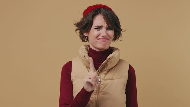Confident young brunette woman 20s wears red hat shirt waistcoat look camera point fingers herself ask say who me no thanks i do not need it isolated on plain pastel beige background studio portrait