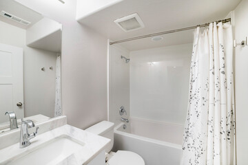 Small windowless white bathroom interior with shower tub combo kit