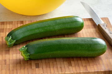 Pair of fresh green whole zucchini on a wooden cutting board