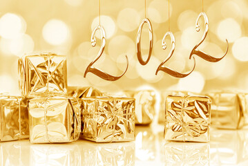 2022, new year card. Small Christmas gifts in shiny golden paper, bokeh lights background