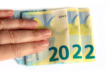 Obraz premium 2022 written with euros bank notes in a hand isolated on white background, new year greetings money concept