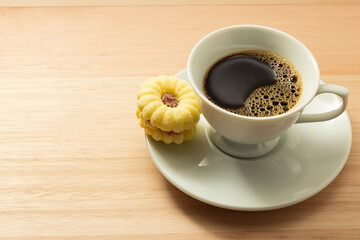 Uma xícara com café e um biscoito amanteigado.