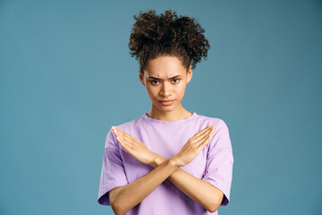 Portrait of angry determined multiracial woman crossing hands and looking at camera with...