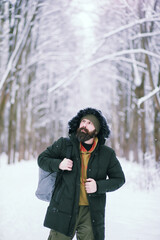 Bearded man in the winter woods. Attractive happy young man with beard walk in the park.