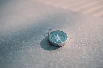 Round stylish compass on concrete background, search direction with compass in summer mountains, point of view. © Shi 