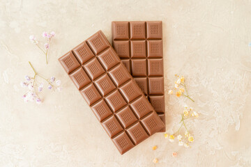 Handmade milk chocolate bar, copy space. Brown bitter craft chocolate with flowers on white...