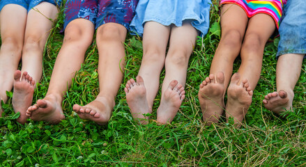 Children's feet lie on the grass. Selective focus.