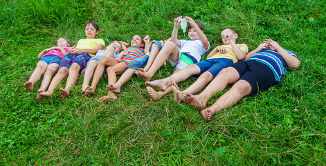 Children's feet lie on the grass. Selective focus.