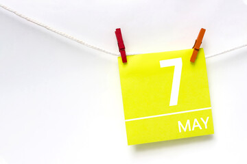 May 7th. Day 7 of month, Calendar date. Paper cards with calendar day hanging rope with clothespins on white background. Spring month, day of the year concept.