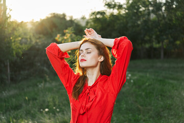 attractive woman in red dress posing in nature green grass