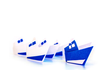 Obraz premium Leadership concept using blue paper ship isolated on white background.