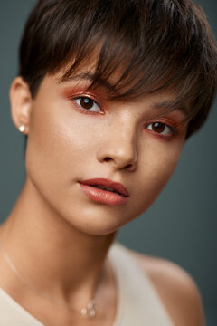 Portrait of beautiful young woman with short hair and and nice makeup on her face isolated on studio background