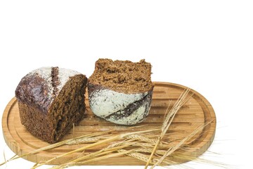 Close up view of cut dark loaf bread and spikelets of rye on a cutting board isolated on white background. Sweden.