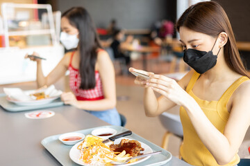Young attractive asian teen female influencer, foodie blogger take photo of food .keep social distance for protect infection from coronavirus covid-19, restaurant and social distancing concept.