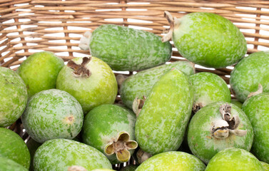 Several ripe sweet feijoa fruits with a basket, close-up, isolated on white.