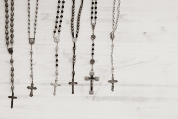 Multiple rosaries hanging on a white background