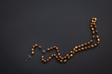 Isolated rosary with wood beads on a black background with copy space