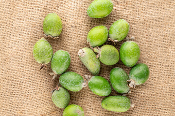 Several fragrant sweet feijoa fruits on sacking, close-up, top view.