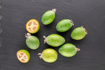 Several fragrant sweet feijoa fruits on a slate stone, close-up, top view.
