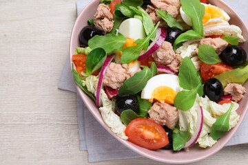 Bowl of delicious salad with canned tuna and vegetables on white wooden table, top view