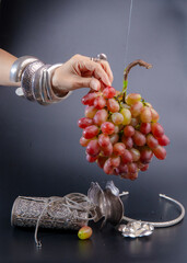 A bunch of fresh grapes, and a woman's hand is reaching for it.