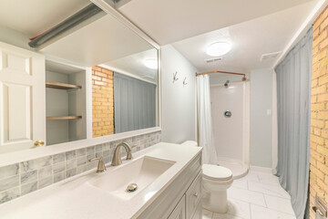 Fototapeta na wymiar Interior of a bathroom with corner shower stall near the gray shower curtain