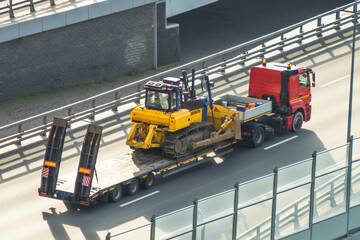 Bulldozer on a heavy platform for transportation. Long bed truck trailer for transporting heavy construction equipment.