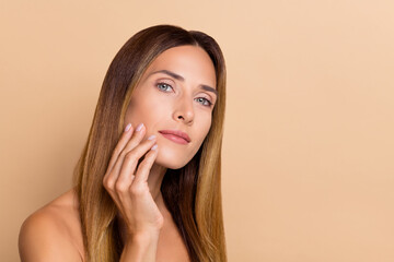 Portrait of attractive brown-haired woman touching shine perfect tone skin cosmetic solution isolated over beige pastel color background