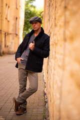 A man in a coat and cap walks around the city.