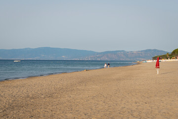 Fototapeta premium Senior couple walking on a sandy beach together, Calabria south of Italy