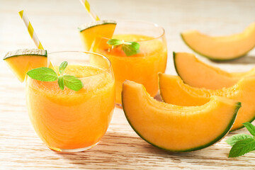 vitamin drink or melon smoothie with fresh cantaloupe melon and mint on a wooden table.