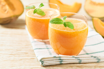 Homemade smoothie with fresh melon and mint on a wooden table.