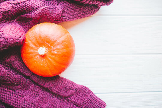 Dark sweater and pumkin on white wood background in autumn