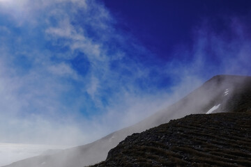 dark blue sky and current with white fog at a mountain while hiking