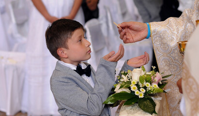 Gives holy communion to faithful boy.