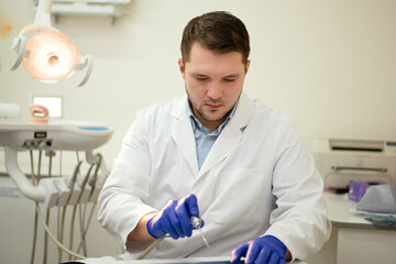 Male dentist smiling and holding tools in his hands. High quality photo