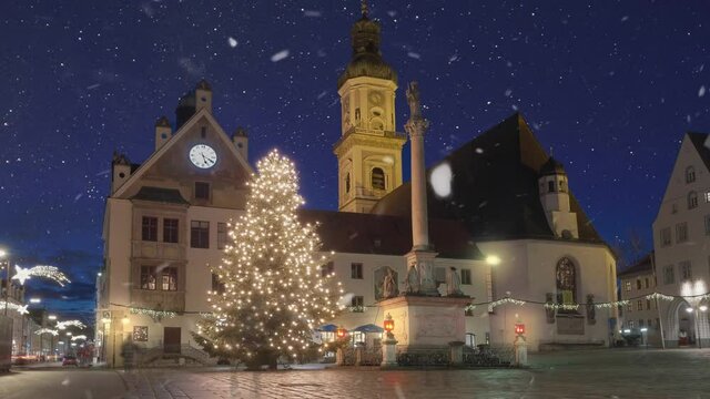 Beautiful christmas tree in front of church at blue hour with snow falling