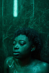 African young woman in depression leaning on the wall while washing in the shower