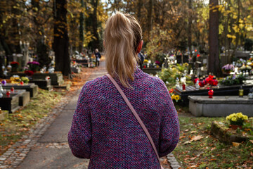 Young woman walking through the cemetery, contemplating during All Saints' Day. Remembering her...