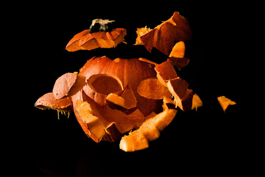 Halloween pumpkin exploding pieces. Decorative Jack-o'-lantern on black background.