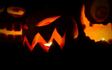 Carved Halloween pumpkins, jack lantern (Jack-o'-lantern). Spooky laughing, scary heads in the darkness.