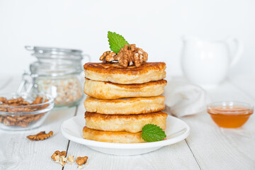 A stack of pancakes with mint, nuts and honey in close-up on a white background.