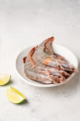 Tiger prawns with lime. Raw seafood on a light background. Fresh shrimp in a plate
