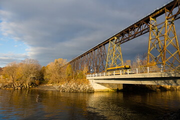 School bus crossing bridge over the Cap-Rouge River, with a striking railway trestle bridge in the background, Cap-Rouge area, Quebec City, Quebec, Canada