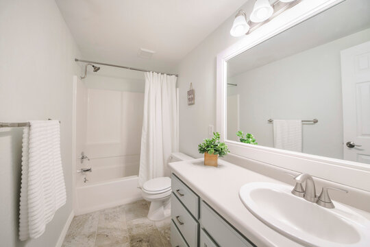 Windowless white minimalist bathroom interior with marble tile flooring