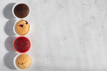 Fototapeta na wymiar Varied, bright tasty cupcakes on a gray background.